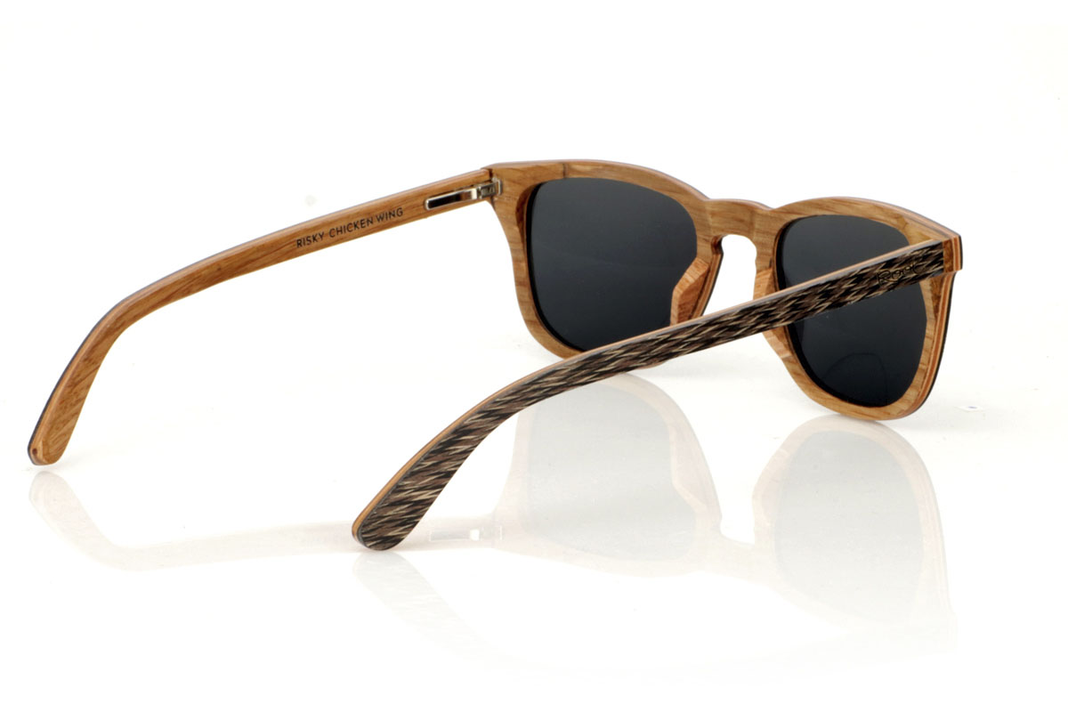 Gafas de Madera Natural de Jichimu RISKY. Las gafas de sol de madera RISKY combinan una forma clásica que favorece a todos los tipos de rostro con un tamaño más contenido, creando un accesorio versátil y siempre en tendencia. Están meticulosamente fabricadas utilizando una técnica de laminado a tres bandas: Madera Chicken Wing negra en el exterior, arce en el centro que aporta luminosidad, y roble en el interior, ofreciendo una resistencia excepcional. Las patillas replican este patrón tricolor, garantizando coherencia y estilo en todo el conjunto. Lo que realmente hace destacar a las RISKY es la textura única de su frontal, acentuada con remaches de roble que capturan la mirada. Con medidas de 140x47mm y un calibre de 49, estas gafas son el equilibrio perfecto entre comodidad y declaración de estilo. Venta al Por Mayor y Detalle | Root Sunglasses® 